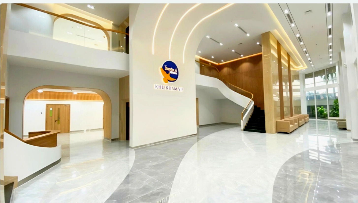 Nội thất sảnh khu khám VIP bệnh viện: trần cao, cầu thang cong, vách gỗ laminate