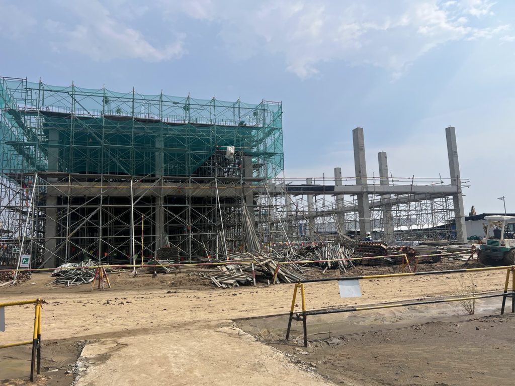 Reinforced concrete factory office block under construction with safety-netted scaffolding