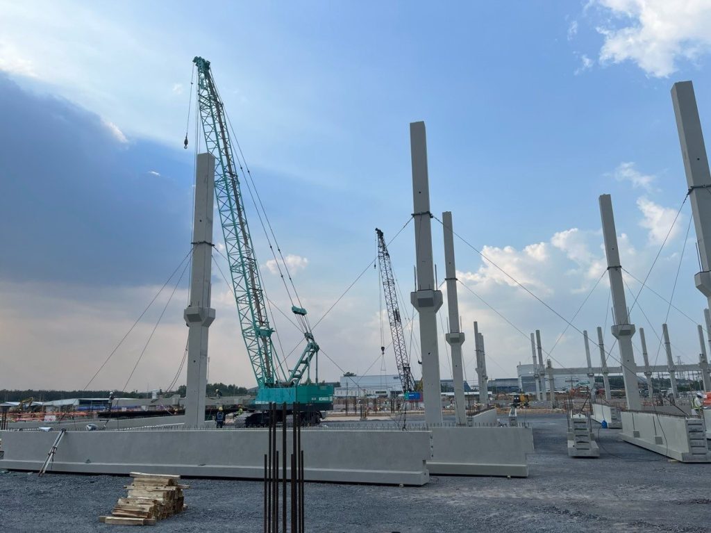 Erecting precast concrete columns with a crawler crane on a factory site