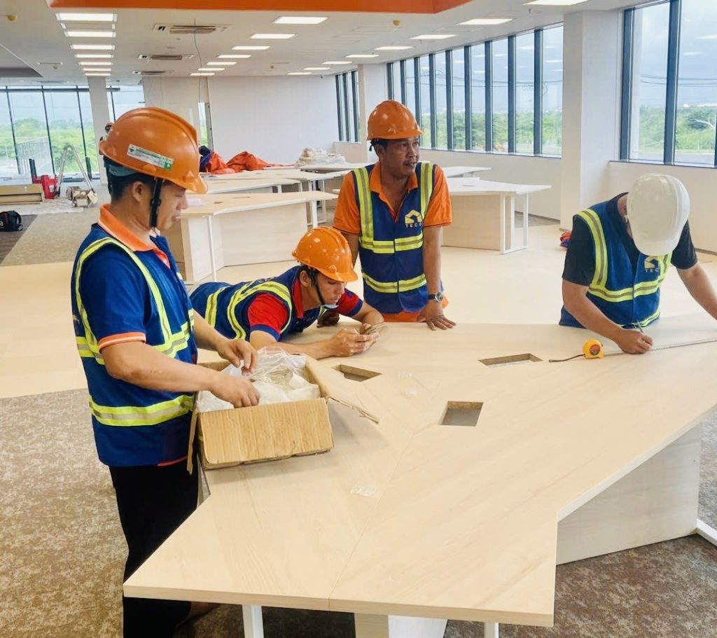 TECO crew assembling team workstations in the open-plan area of a factory office