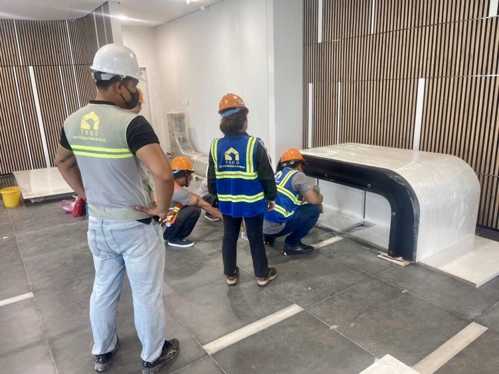 TECO crew aligning the reception counter in a factory office lobby with timber slat walls
